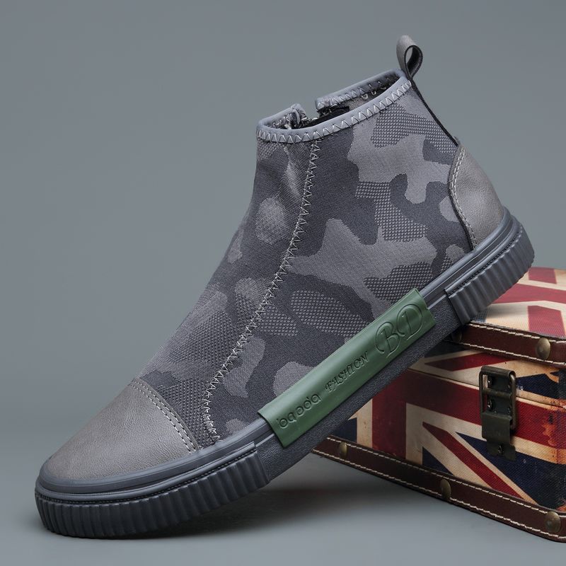 Modern gray camouflage ankle sneaker with green sole label placed on vintage Union Jack suitcase