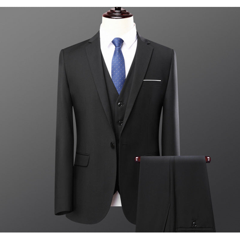 Black three-piece men's suit with blue patterned tie on mannequin against gray background