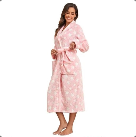 Woman wearing a cozy pink star-patterned fleece robe with pockets, tied waist, ankle length