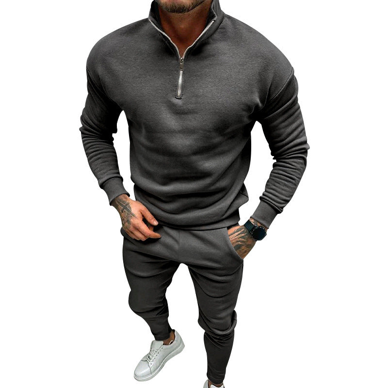 man wearing dark grey quarter-zip sweatshirt and matching jogger pants with white sneakers
