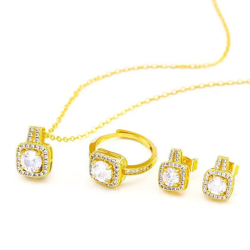 Gold jewelry set with cubic zirconia including pendant necklace, ring, and stud earrings on white background