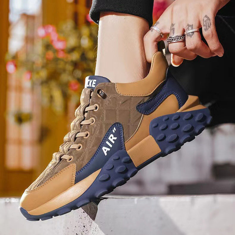 Close-up of a hand holding a brown and navy athletic sneaker with AIR branding outdoors