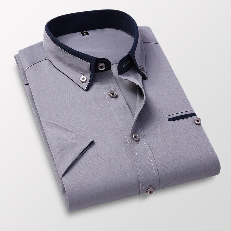 Folded grey dress shirt with navy blue collar and button details on white background