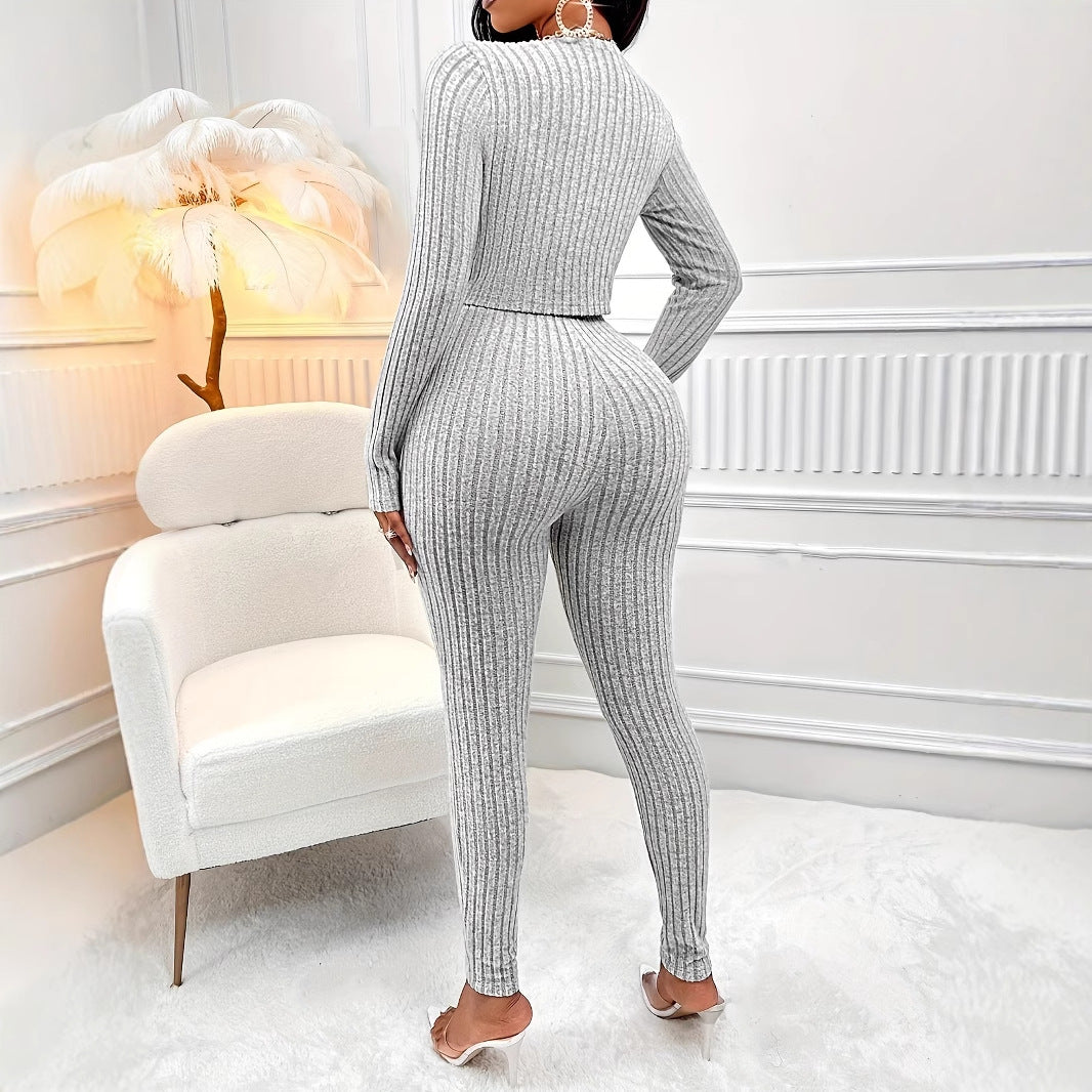 Woman wearing gray ribbed knit two-piece outfit with long sleeves, standing in modern white room