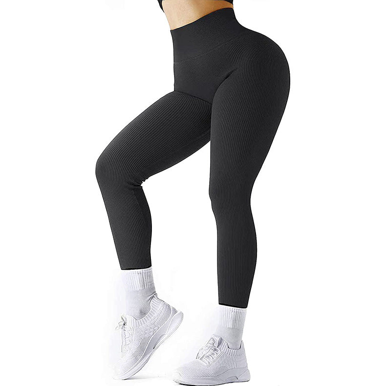 Woman wearing black ribbed high-waisted leggings and white sneakers on white background