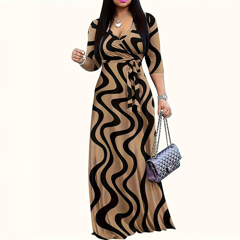Woman wearing beige and black wavy print maxi dress with long sleeves, holding a silver quilted handbag