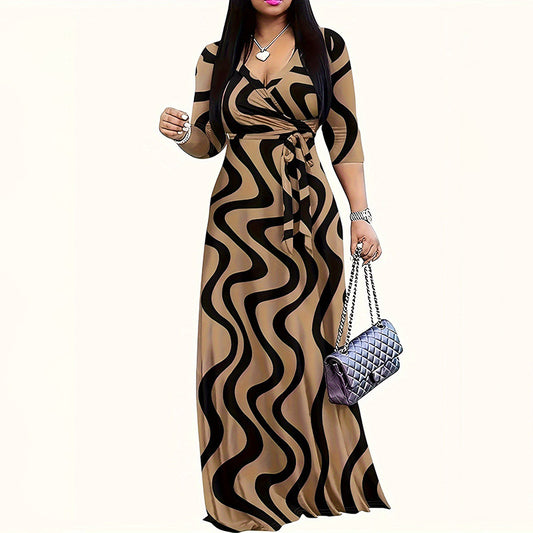 Woman wearing beige and black wavy print maxi dress with long sleeves, holding a silver quilted handbag