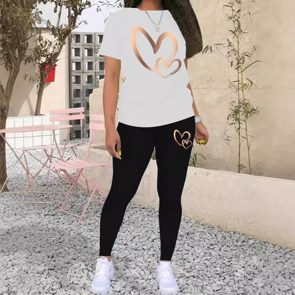 Woman wearing white t-shirt and black leggings with rose gold heart designs standing outdoors on gravel