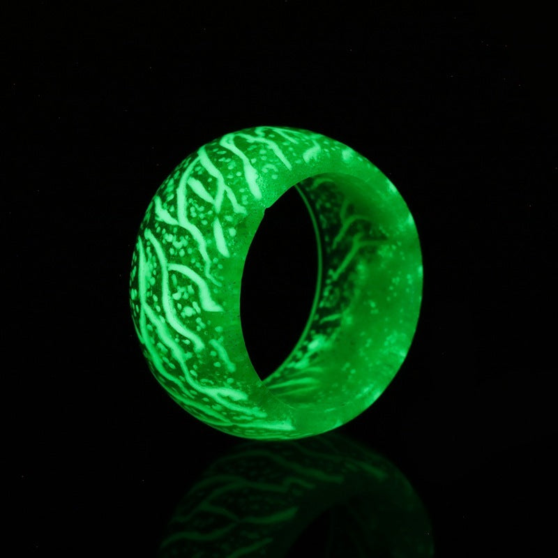 Glowing green resin ring with white veins, illuminated against black background
