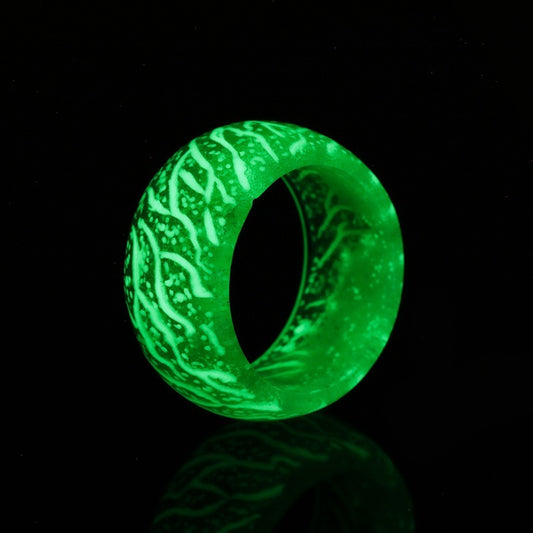 Glowing green resin ring with white veins, illuminated against black background