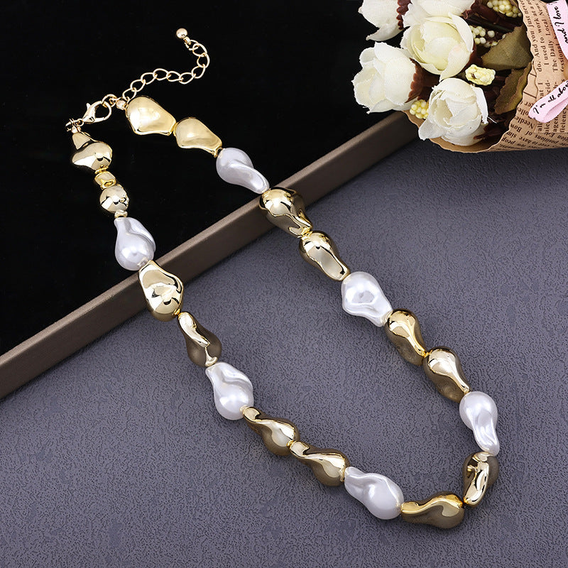 Elegant necklace with irregular gold and white pearl beads on gray and black backgrounds with white flower bouquet