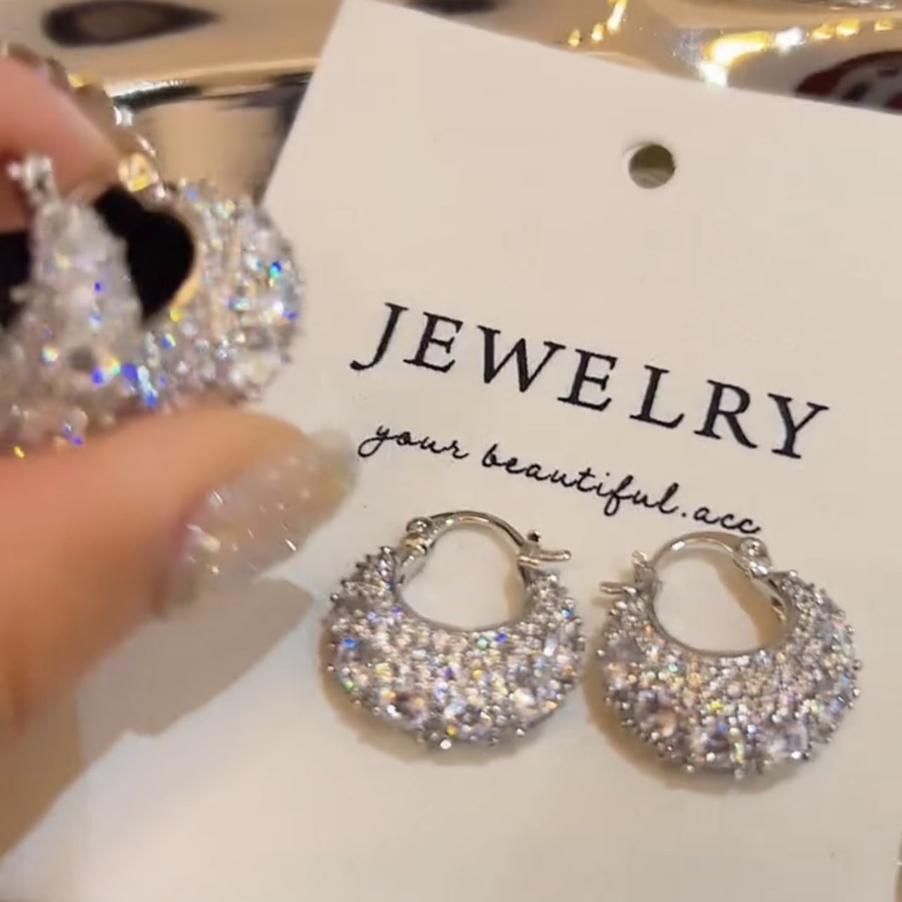 sparkling silver hoop earrings with crystals on white jewelry card