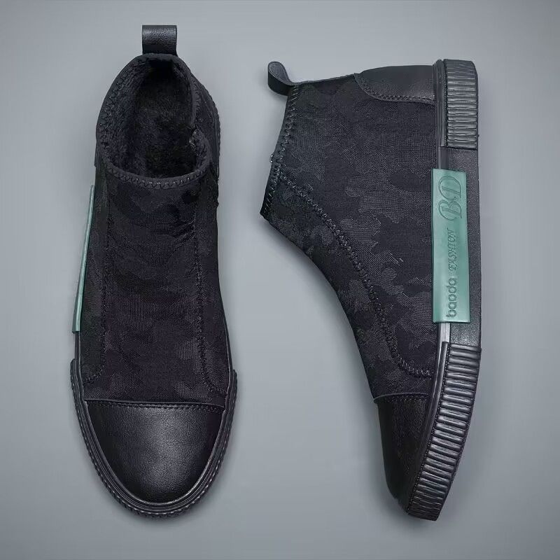 Pair of black high-top sneakers with textured uppers and green brand tag on gray background