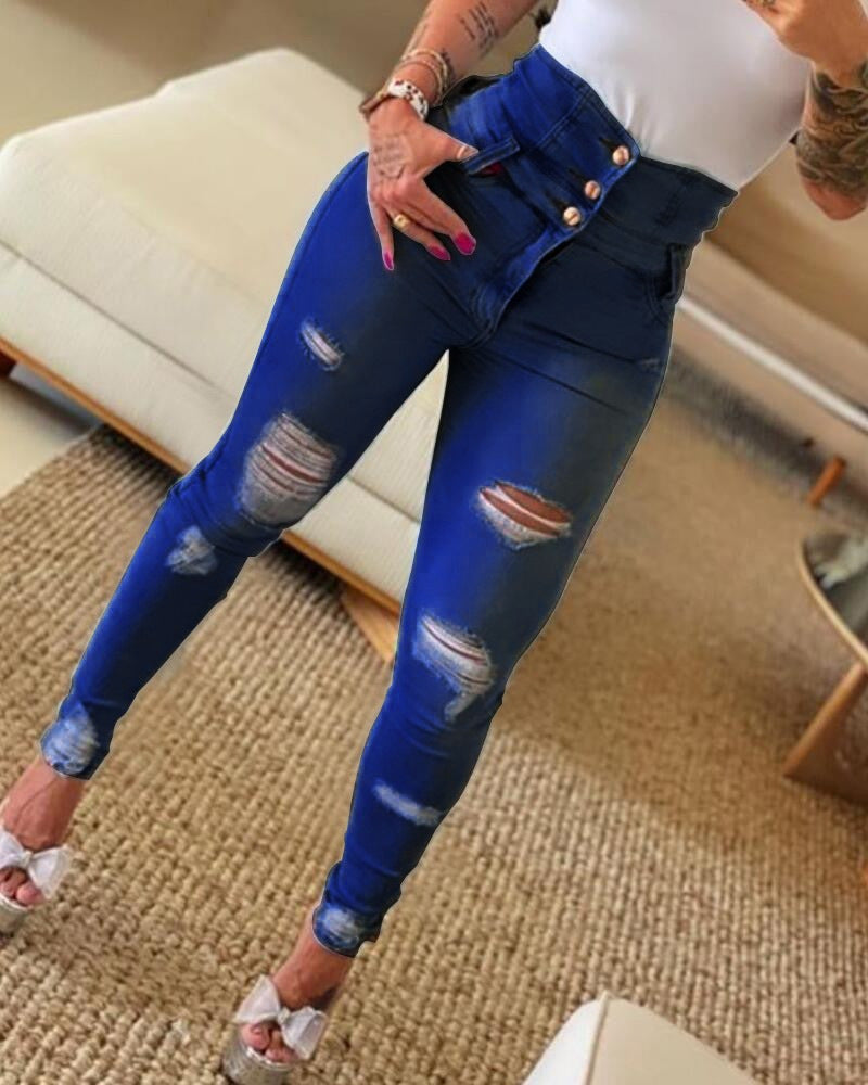 High-waisted distressed blue skinny jeans with button details worn by a woman in a cozy living room