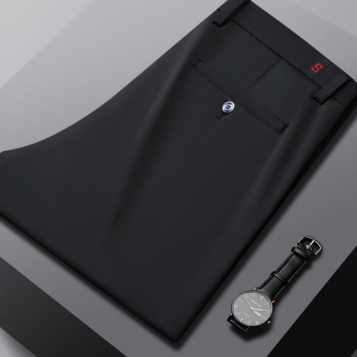 Black folded dress pants with button and waistband detail beside a black leather strap wristwatch on gray surface