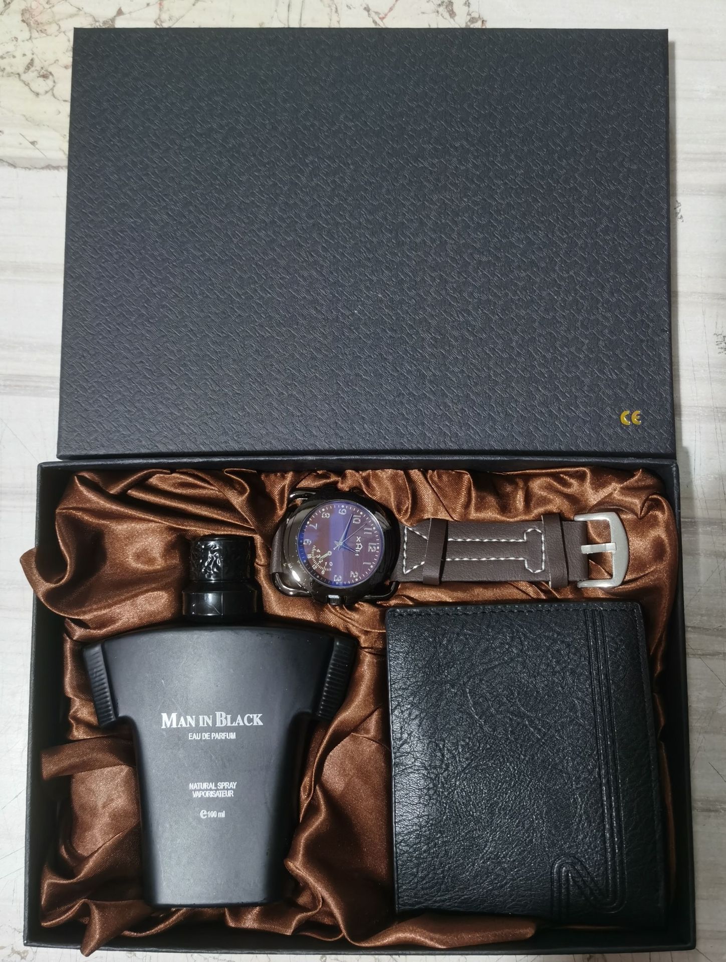 Luxury gift set with Man in Black perfume, brown leather strap wristwatch, and black leather wallet in satin-lined box