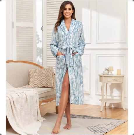 woman in blue patterned plush bathrobe standing in cozy living room with beige sofa and side table