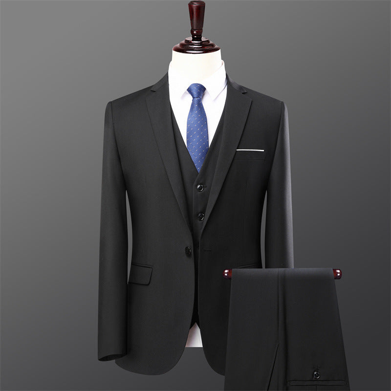 Black three-piece men's suit with blue patterned tie on mannequin against gray background
