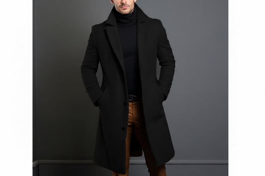 Man wearing black overcoat and black turtleneck sweater with brown pants against gray background
