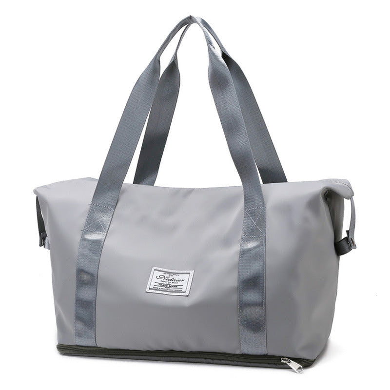 Light gray waterproof duffel bag with wide straps, zipper bottom compartment, and front logo patch