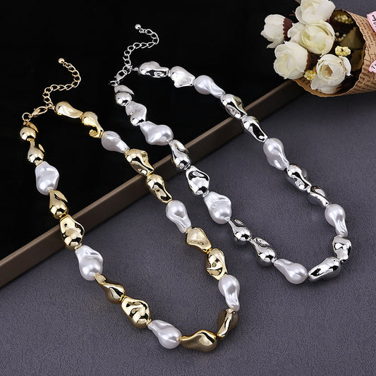 Two elegant beaded necklaces with irregular gold and silver beads paired with white pearls on a gray surface with white flowers