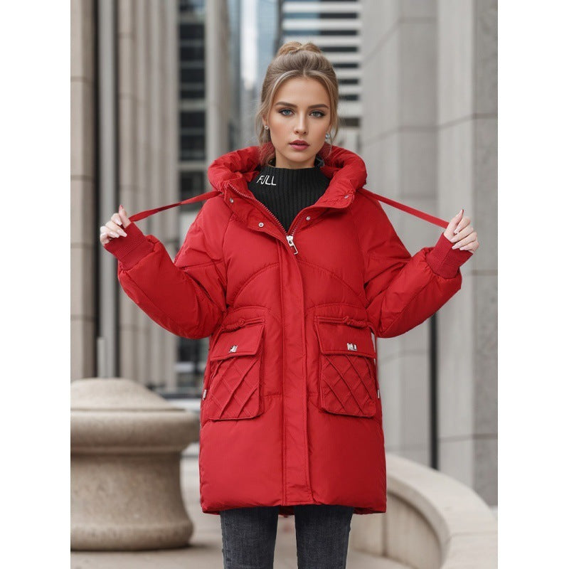 Young woman wearing a red quilted winter coat with hood and large front pockets in urban setting
