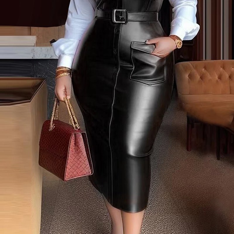Woman wearing a black leather belted midi skirt with pocket detail and white long sleeve shirt, holding a red handbag