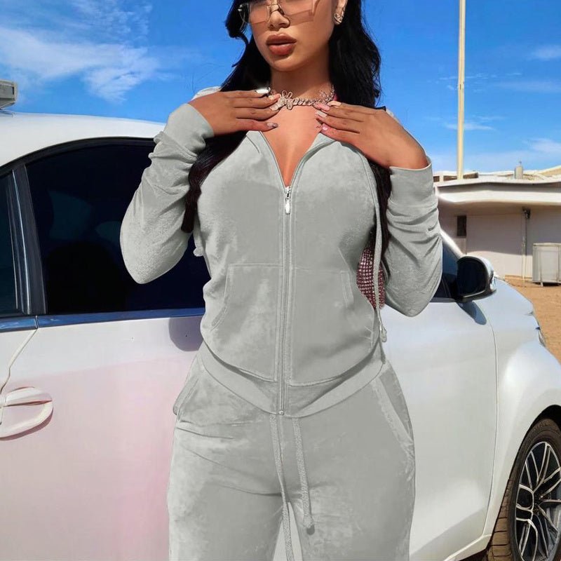 woman wearing light gray zip-up hoodie and matching drawstring pants standing by white car outdoors