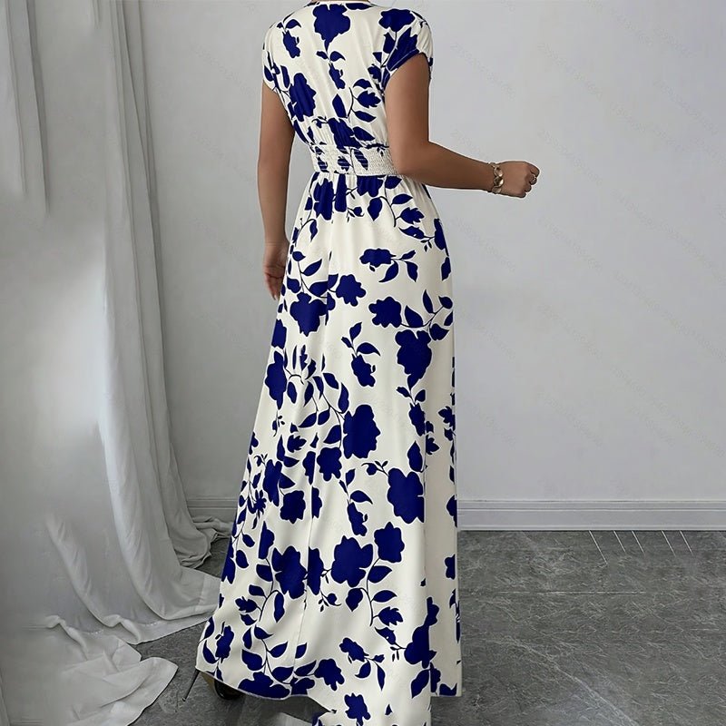 Woman wearing a white maxi dress with blue floral print, short sleeves, and elastic waist, standing indoors