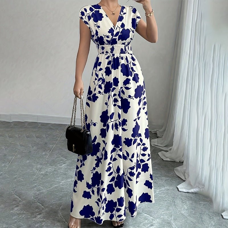 Woman wearing white maxi dress with blue floral print, V-neck, short sleeves, and elastic waist holding black chain bag