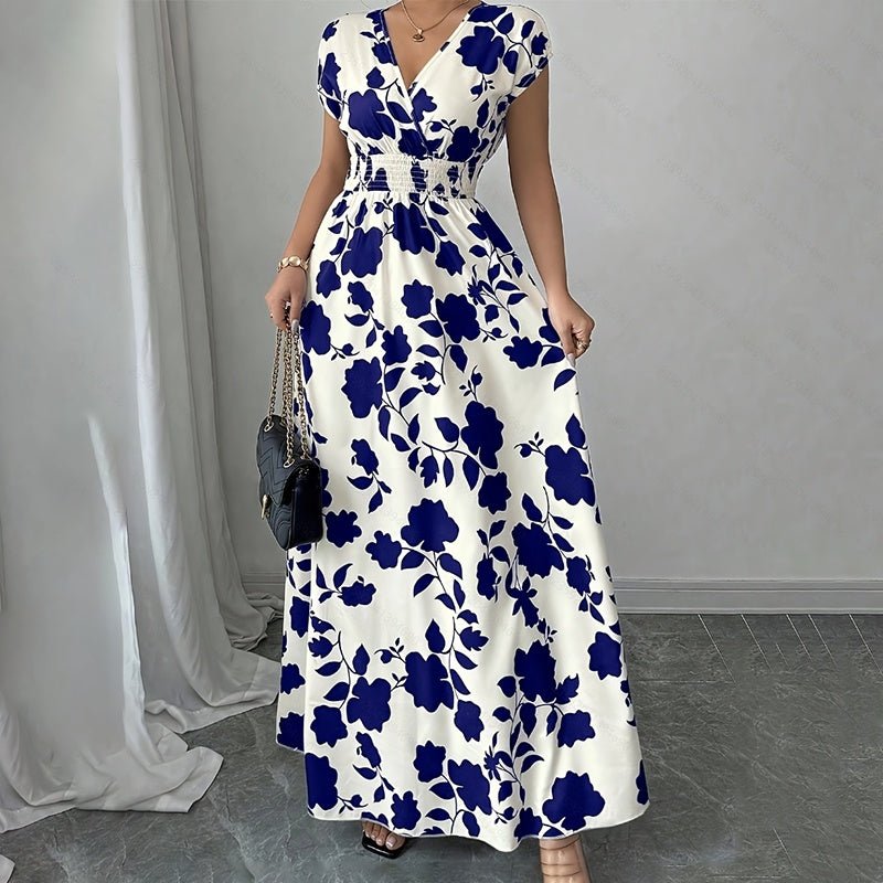 Woman wearing white maxi dress with blue floral print, wrap V-neck, short sleeves, and elastic waist, holding black handbag