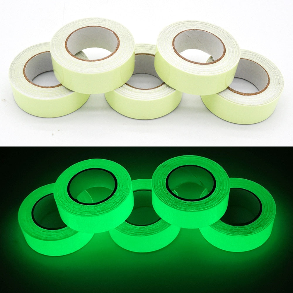 Five rolls of yellow glow-in-the-dark adhesive tape shown in daylight and glowing green in darkness