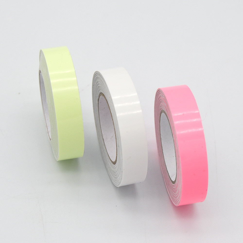 Three rolls of adhesive tape in pale yellow, white, and pink on a white surface