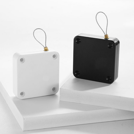 Black and white square keychain holders with metal loop on white geometric platforms