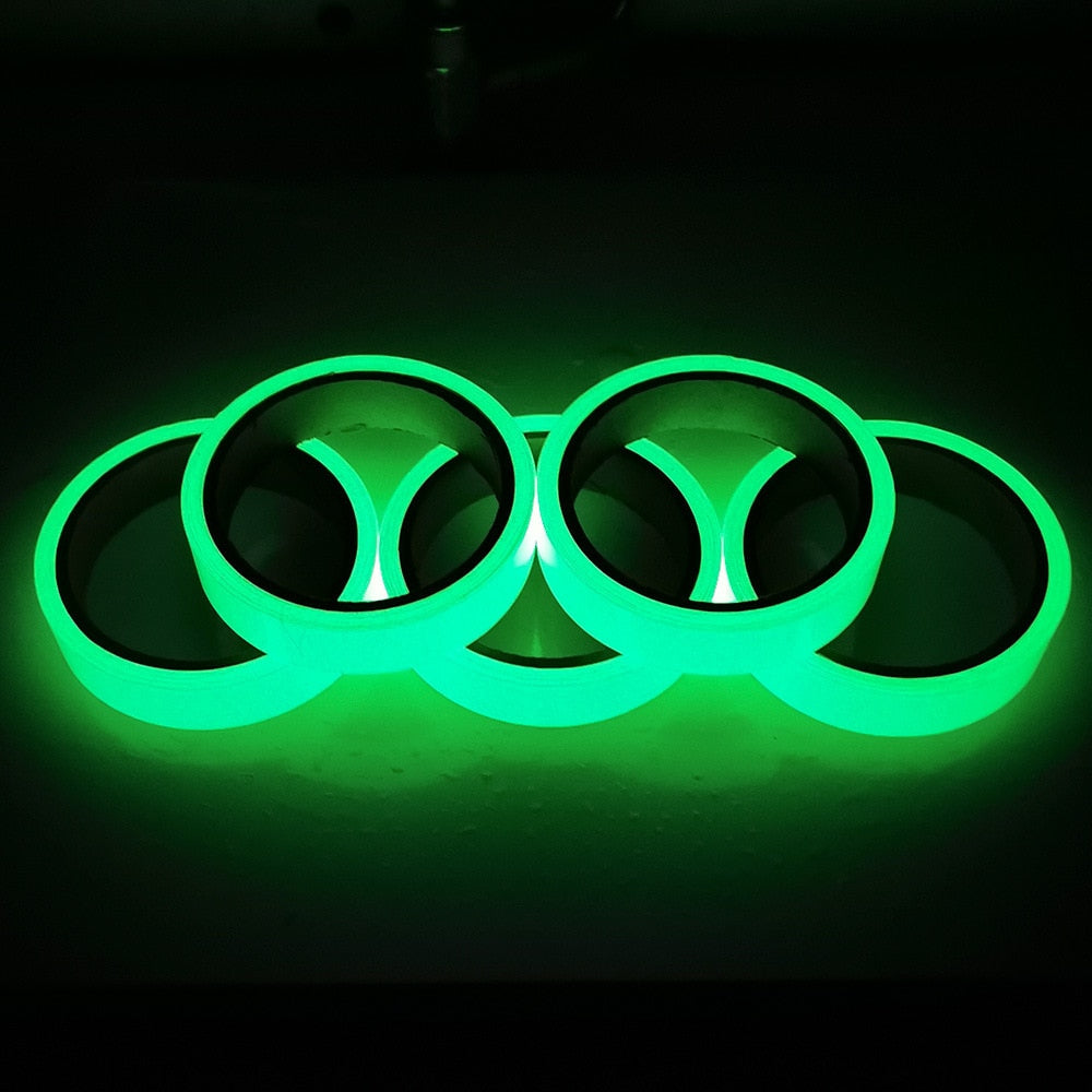 Four rolls of green glow-in-the-dark tape glowing in the dark, arranged side by side